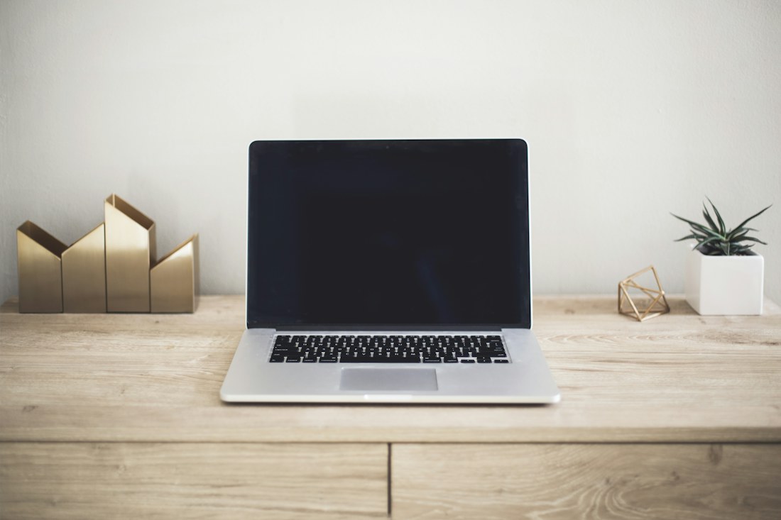 Laptop MacBook abierta sobre un escritorio de madera