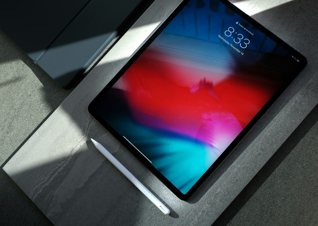 Tableta iPad con su lápiz óptico sobre una superficie de piedra oscura