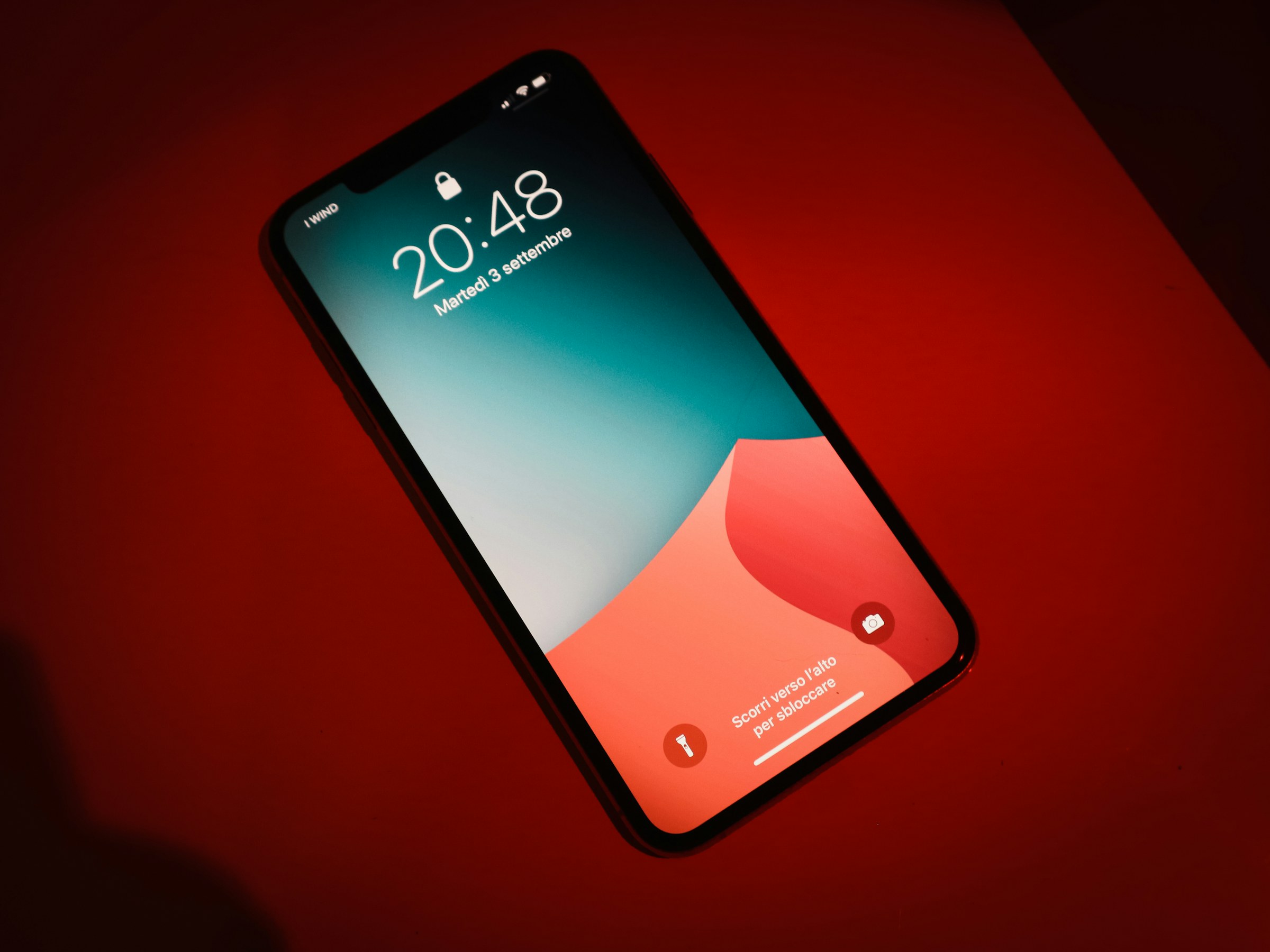 Teléfono inteligente sobre una superficie roja intensa, con la pantalla encendida